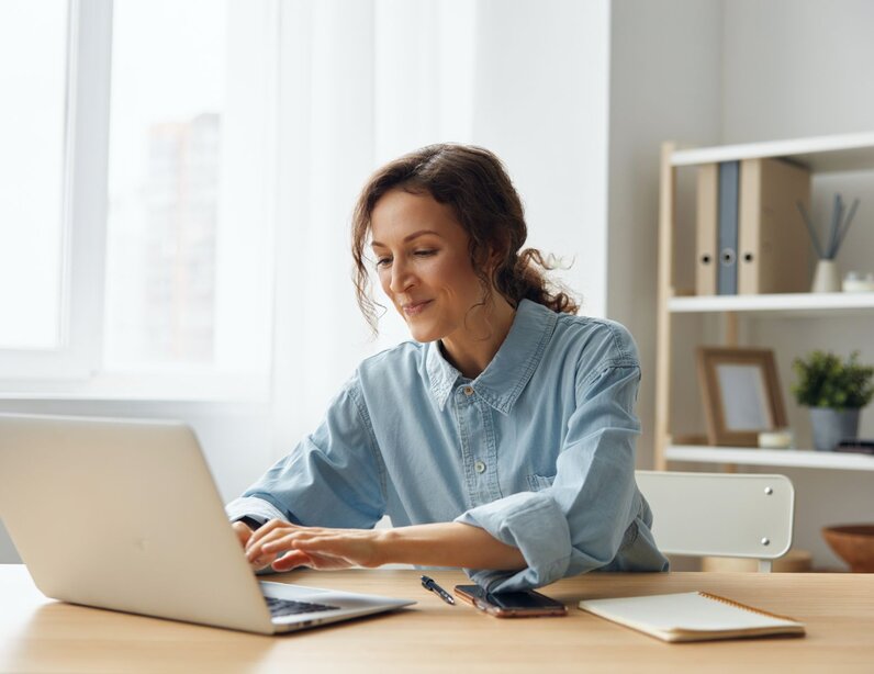 Frau sitzt hinter ihrem Laptop