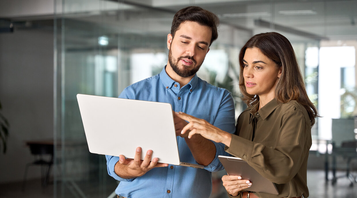 Mann und Frau stehen vor einem Laptop