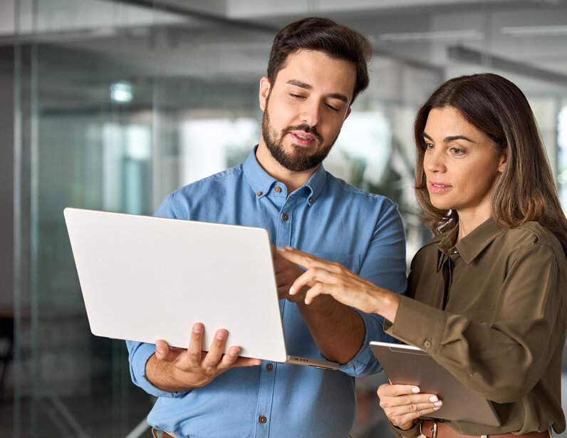 Mann und Frau stehen vor einem Laptop