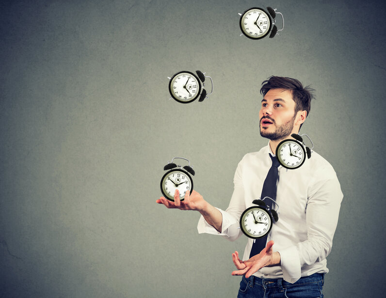 Mann jongliert Uhren und symbolisiert Arbeitszeiterfassung