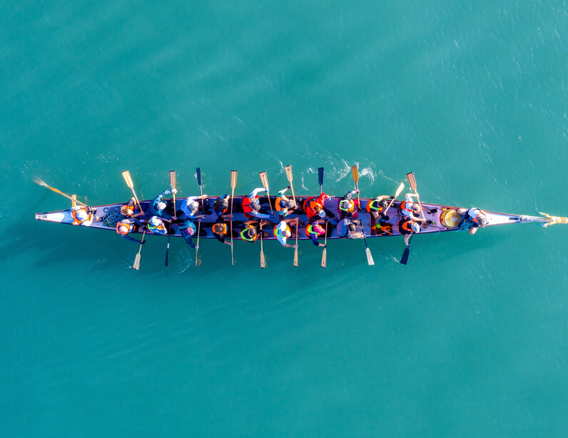 Gruppe sitzt im Ruderboot. Symbolbild für Onboarding